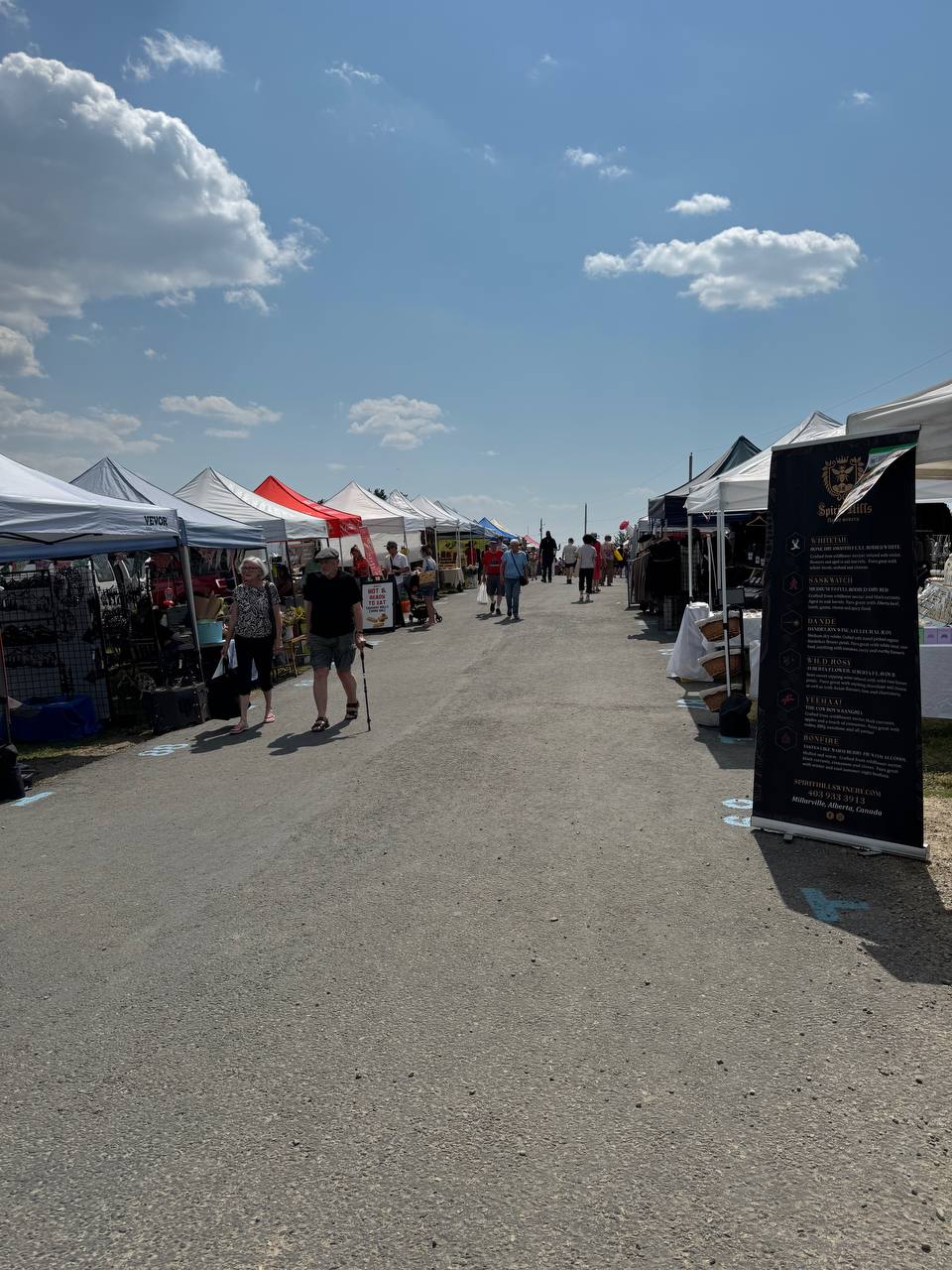 Vendor tents at Bearspaw Farmers Market under a blue summer sky